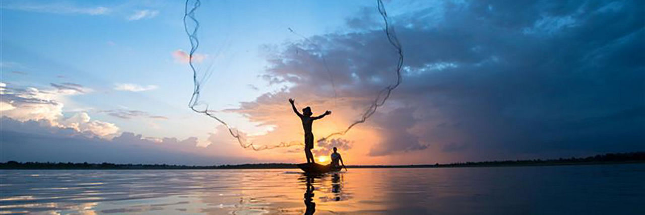 fishermen throwing a fishing net at sunset