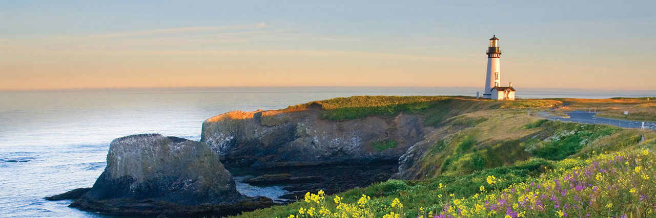 Waves crashing on cliffs with lighthouse in the distance